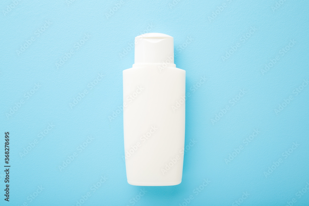 White plastic bottle on light blue table background. Pastel color. Care about face, hands, legs and body skin. Beauty product. Closeup. Empty place for text or logo. Top down view. White plastic bottle on light blue table background. Pastel color. Care about face, hands, legs and body skin. Beauty product. Closeup. Empty place for text or logo. Top down view.