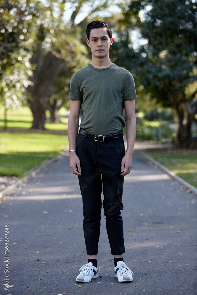 Young man with dark hair standing outside at park Young man with dark hair standing outside at park