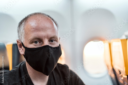 Man wearing face mask sitting in the airplane © eunikas