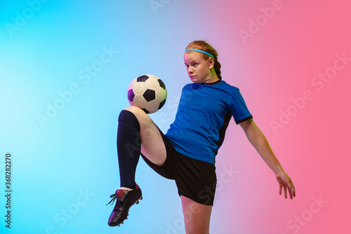 Bouncing ball. Female soccer, football player training in action isolated on gradient studio background in neon light. Concept of motion, action, ahievements, healthy lifestyle. Youth culture. © master1305