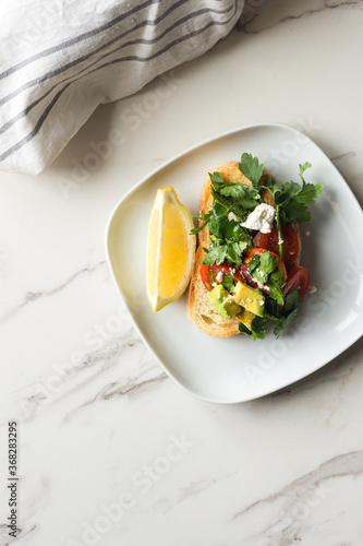 smashed avo on toast, with feta, tomatoes, parsley and lemon photo