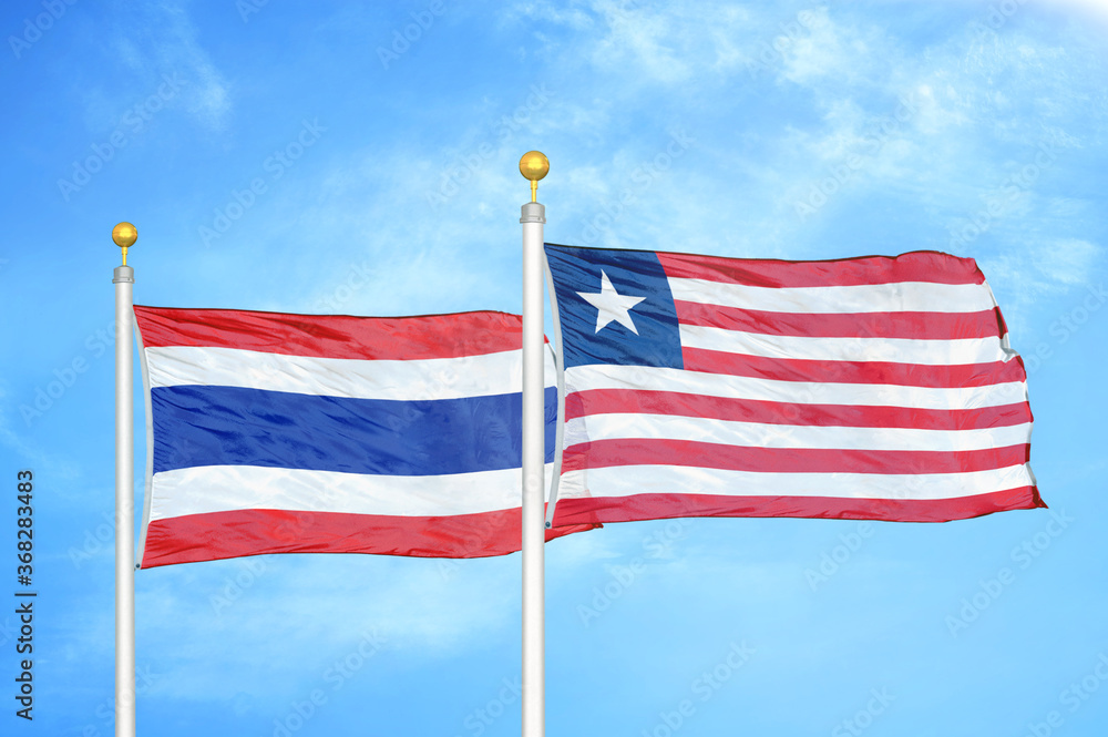Obraz premium Thailand and Liberia two flags on flagpoles and blue sky