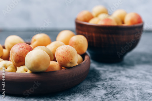 Lots of ripe yellow apricots close up in a crockery on the table