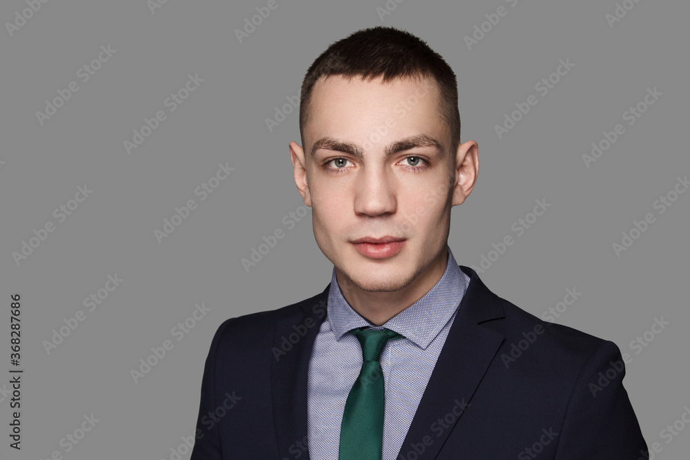 Casually handsome young man. Confident handsome caucasian man in necktie and suit over gray background Casually handsome young man. Confident handsome caucasian man in necktie and suit over gray background