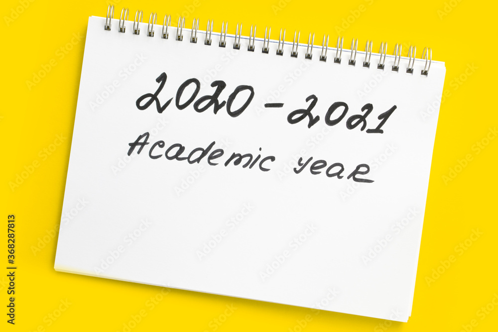 Back to school. 2020 - 2021 academic year. The inscription in a white notebook with a spiral, on a yellow background. Back to school. 2020 - 2021 academic year. The inscription in a white notebook with a spiral, on a yellow background.