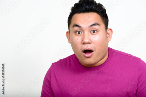 Portrait of young handsome overweight Asian man looking shocked © Ranta Images
