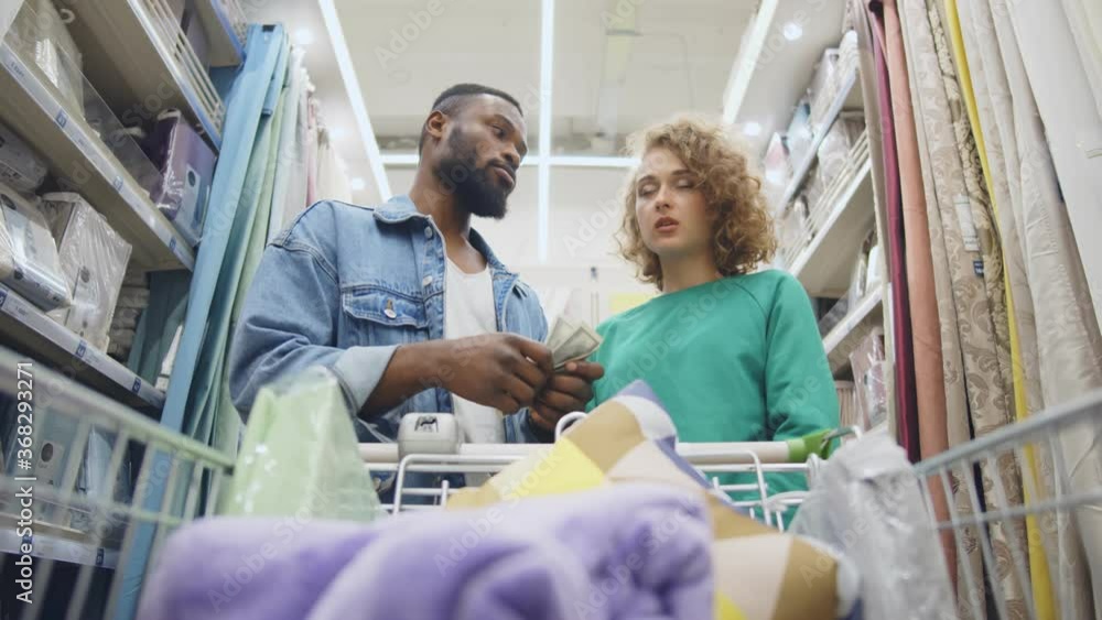 Low angle view of sad young couple with shopping cart having little money to pay Low angle view of sad young couple with shopping cart having little money to pay