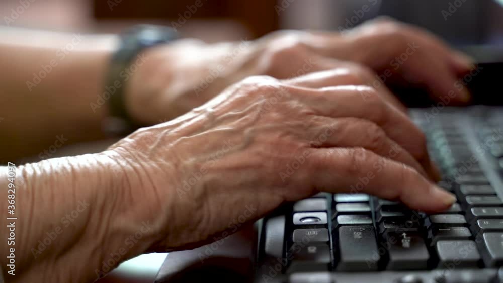 Closeup of elderly woman’s hands with arthritis typing on computer keyboard inside in bright sunlit room. Closeup of elderly woman’s hands with arthritis typing on computer keyboard inside in bright sunlit room.