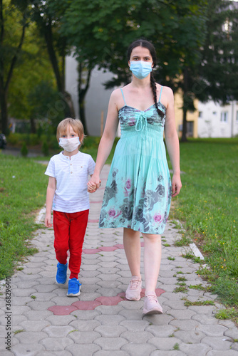 Mother and child wear facemask during coronavirus, flu outbreak. Child and mom in medical mask on a walk.