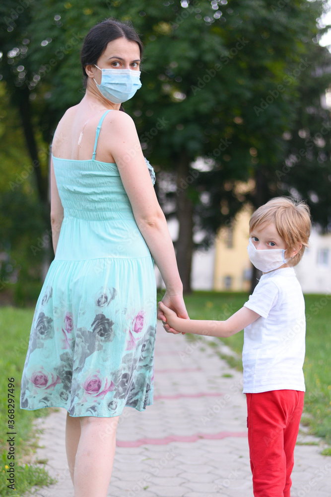 Mother and child wear facemask during coronavirus, flu outbreak. Child and mom in medical mask on a walk. Mother and child wear facemask during coronavirus, flu outbreak. Child and mom in medical mask on a walk.