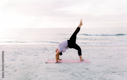 young woman doing yoga on the beach , curvy woman doing yoga 