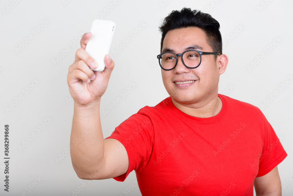 Portrait of happy young overweight Asian man taking selfie Portrait of happy young overweight Asian man taking selfie