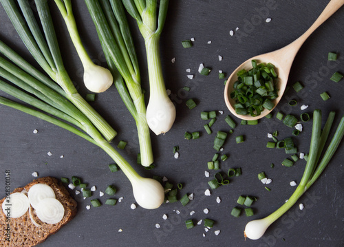 Pile of green onion and herb chopped in wooden spoon. Stone background. Top view. photo