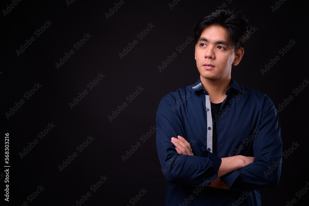Young handsome Asian man against black background Young handsome Asian man against black background