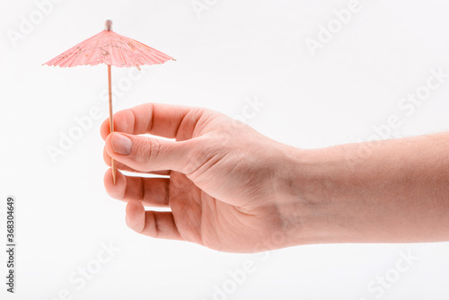 Hand holding a paper umbrella, isolated on white