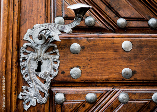 An ornate door lock and handle on an old exterior door in Europe.