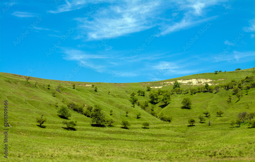 landscape with blue sky and a hill with green grass