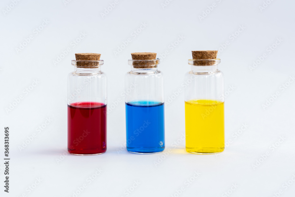 Three closed vials with colored contents on a white background. Red, blue, yellow.