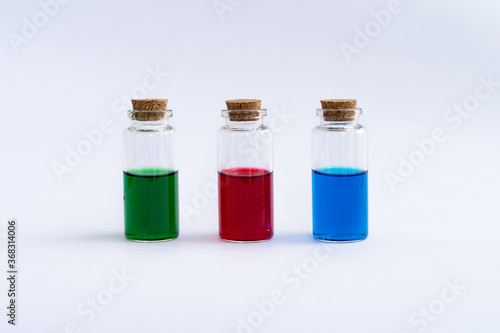 Three closed vials with colored contents on a white background. Green, red, blue.