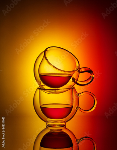 Two glass cup of tea on yellow and red background. Creative concept of tea. © Tatyana Sidyukova