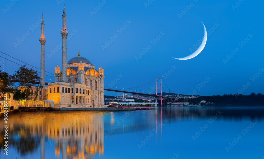 Ortakoy mosque and Bosphorus bridge with crescent moon at twilight blue hours - Istanbul, Turkey