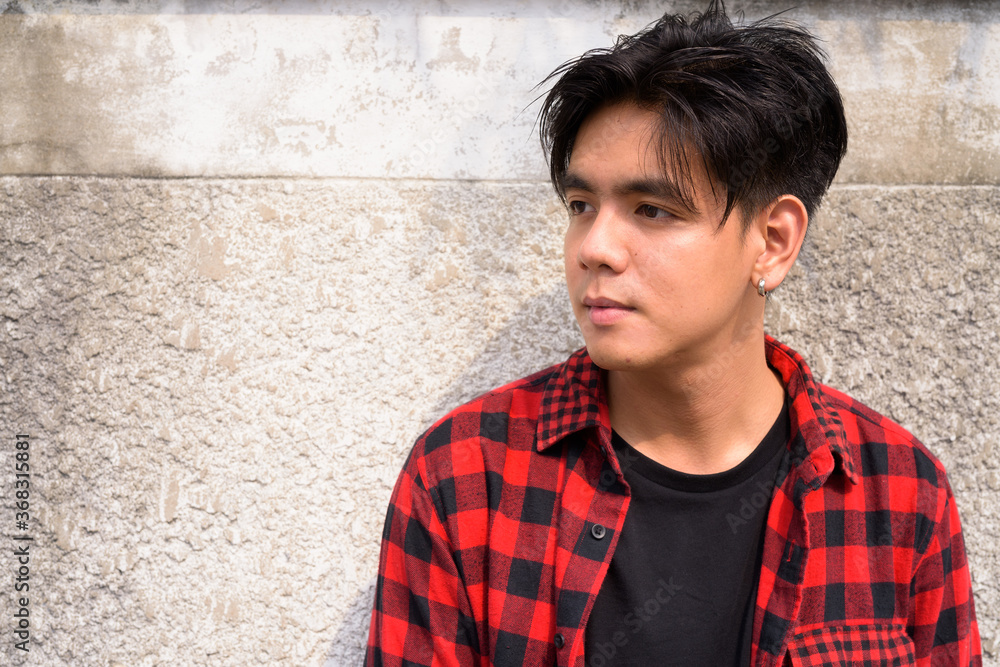 Fototapeta premium Young handsome Asian hipster man in the streets outdoors