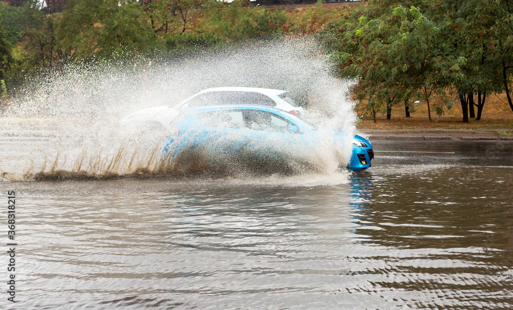Naklejka premium Driving cars on a flooded road during flooding caused by torrential rains. Cars float on water flooded streets. The disaster in Odessa