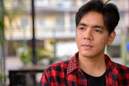 Young handsome Asian hipster man at the coffee shop