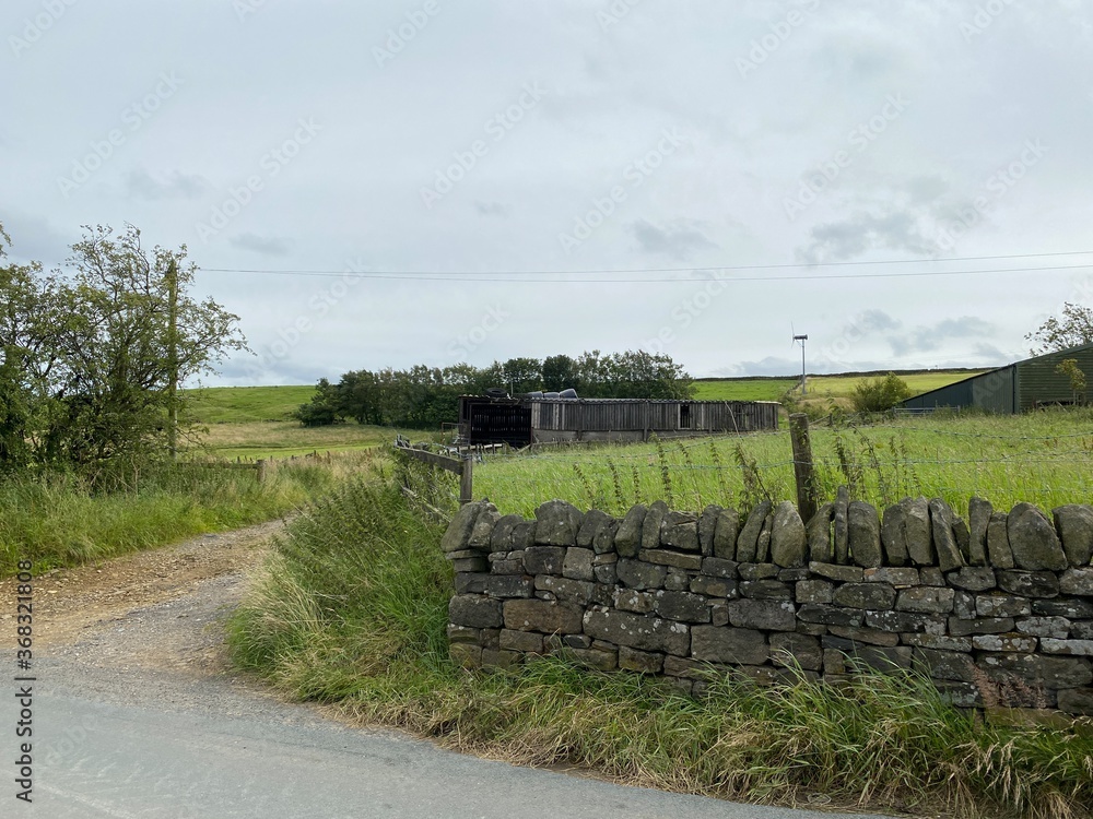 Obraz premium Old farm outbuildings, within dry stone walls, and an open gate, high on the hills above, Sowerby Bridge, Yorkshire, UK