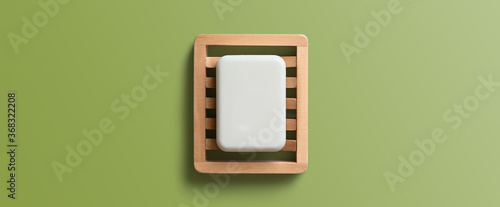 Obraz na plátně White bar of soap in wooden dish on a green background