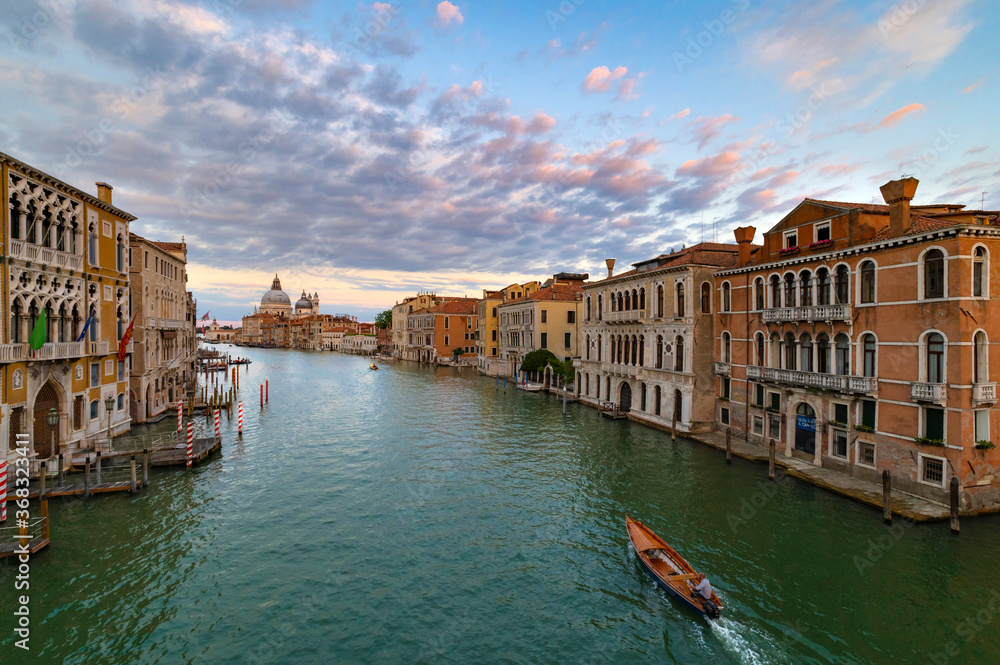 A wonderful evening shot of the Canal Grande seen from the Ponte dell'Accademia. On the background the church of Santa Maria della Salute. Sunset with pink and blue clouds, green water. Venice, Italy.