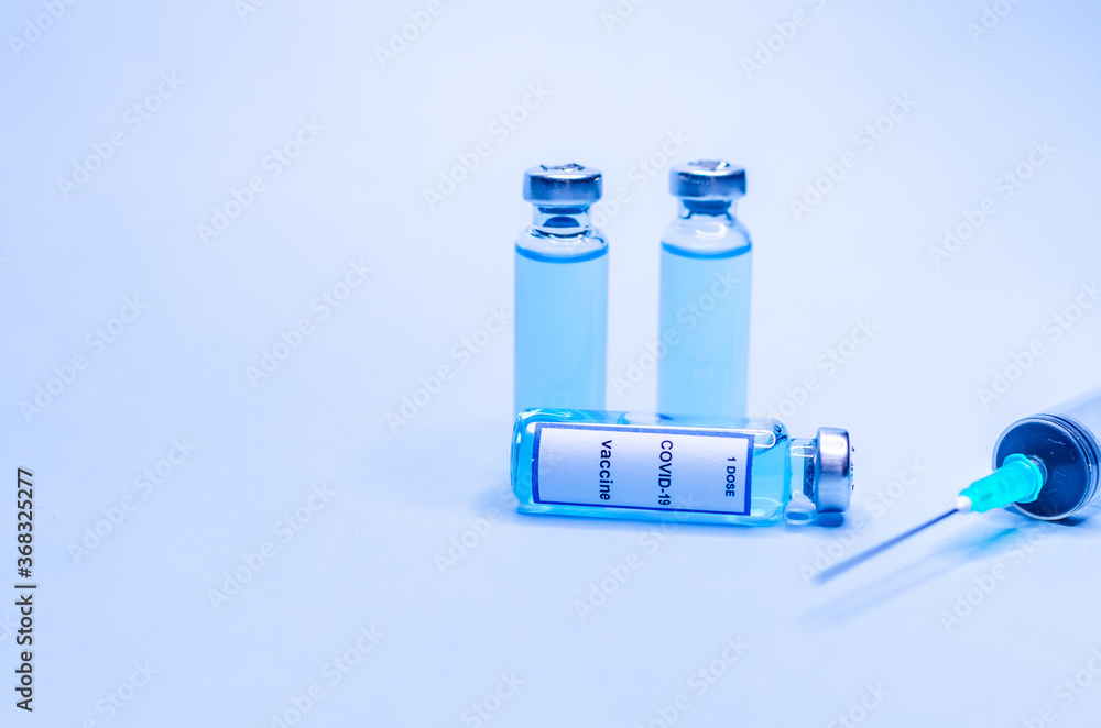 Coronavirus vaccine in glass vials with a syringe on a blue background. Coronavirus vaccine in glass vials with a syringe on a blue background.