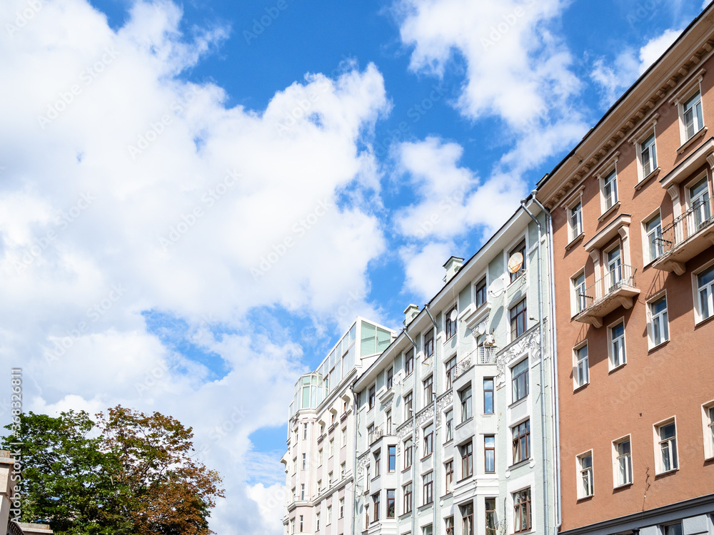facades of apartment houses and blue sky with white clouds on sunny summer day on Malaya Nikitskaya street in Moscow city
