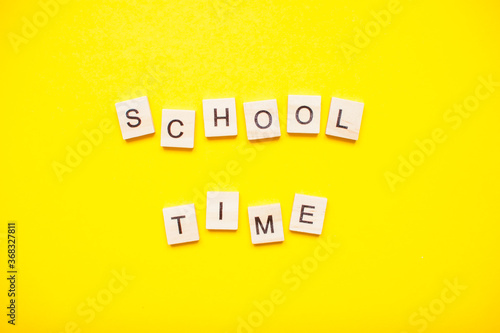 Words from wooden blocks "school time" on bright yellow background