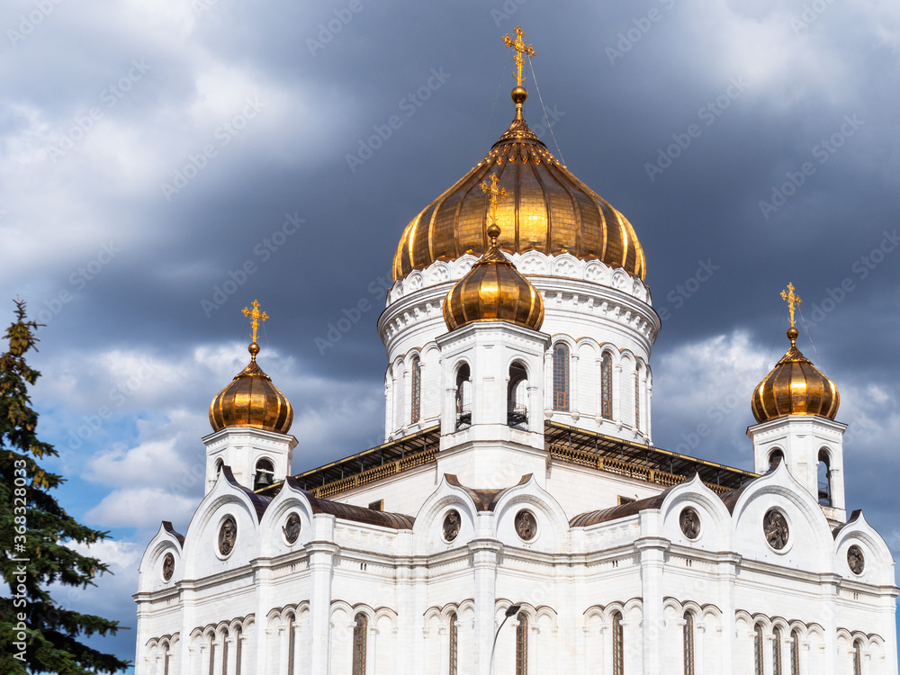 view of Cathedral of Christ the Saviour from west side under dark gray rainy clouds in Moscow city in sunny summer evening