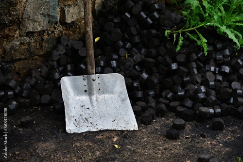 Old aluminum shovel near a pile of coal. Black coal briquettes ready for storage. Black coal heating. Preparing for winter. photo