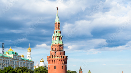 view of spire of Vodovzvodnaya tower of Kremlin under dark blue rainy clouds during city sightseeing tour on excursion bus in Moscow city on sunny summer day