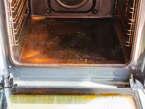 cleaning oven in home kitchen - view of inner chamber of oven with carbon deposits on bottom and walls