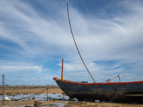 Small fishing boats of villagers in the area parked on Phla beach, Rayong province after going out to fish at night. On a blue day photo