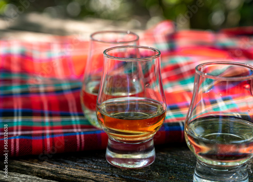 Fototapeta Naklejka Na Ścianę i Meble -  Tasting of different Scotch whiskies on outdoor terrace, dram of whiskey and red tartan