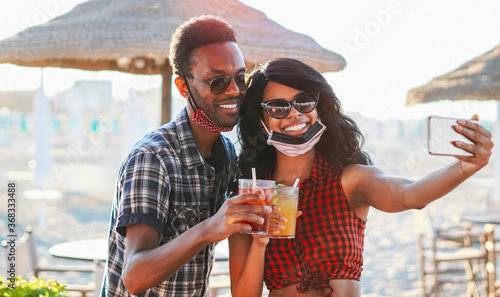 Photography African american couple taking selfie in beach party - Young friends with face m