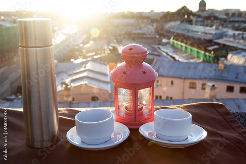 Thermos and tea cups on the rooftop before sunset photo