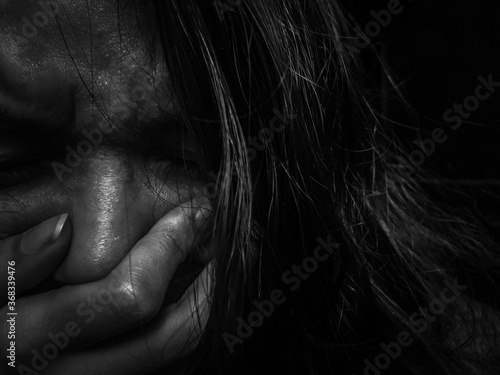 Scared woman crying on dark background - Covering the sad face with the hand
