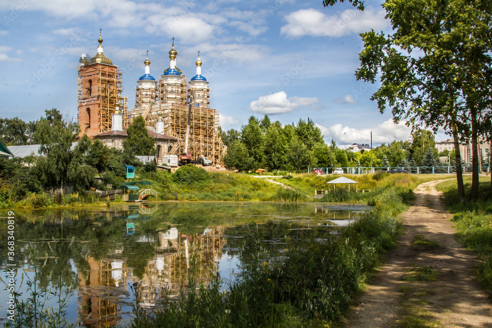 Restoration of old white orthodox church near dirty pond