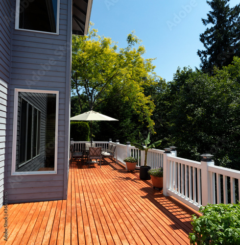 Obraz na plátně Outdoor home wooden deck during lovely summer day with seasonal garden