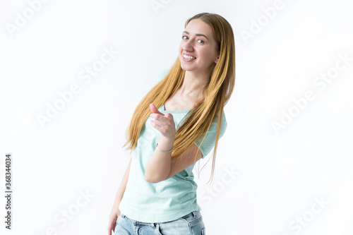Portrait of a smiling girl who stands and points forward the index finger of her hand on a white background