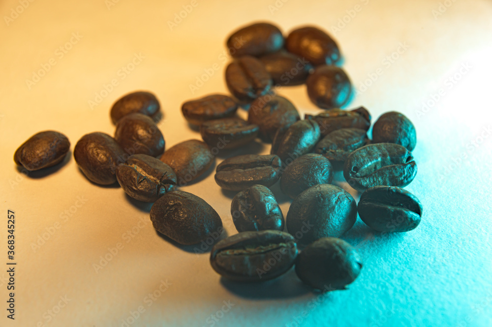 A small heap of roasted coffee beans, isolated on an orange and teal background A small heap of roasted coffee beans, isolated on an orange and teal background