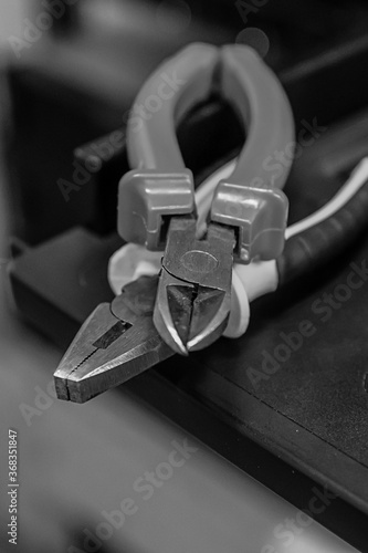 Black pliers toned for working with metal, industrial background