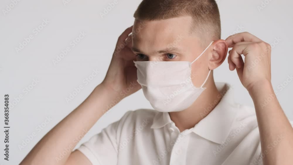 Side view shot of attractive casual guy wearing medical mask on camera over white background. Safety concept Side view shot of attractive casual guy wearing medical mask on camera over white background. Safety concept