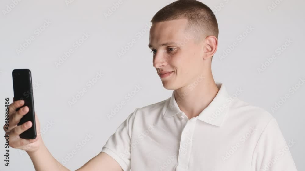 Young attractive smiling man talking on video chat with friends on smartphone over white background Young attractive smiling man talking on video chat with friends on smartphone over white background